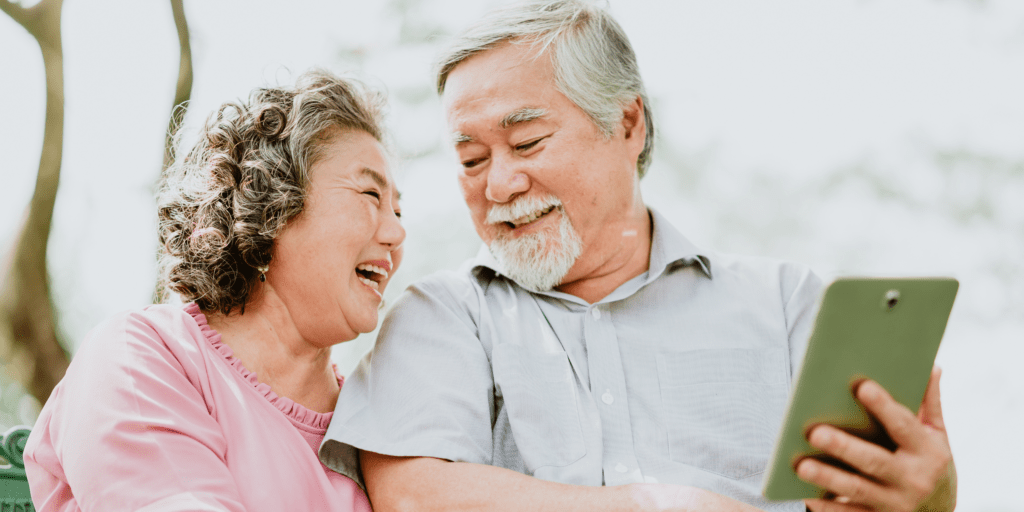Smiling senior couple using a tablet together, representing compassionate in-home care services from Loving Hands Homecare Agency in Eaton Rapids, Michigan.