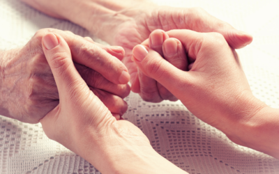Caregiver holding an older adult's hands while providing compassionate in-home care and support.