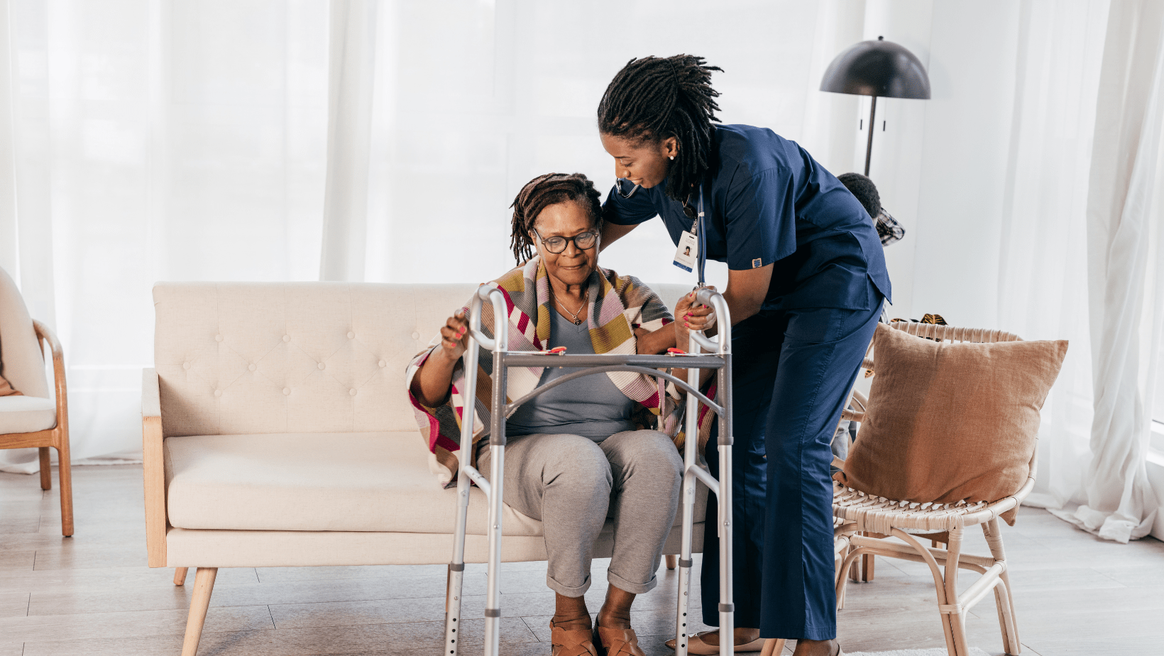 Caregiver assisting an older adult with a walker at home in Lansing, Michigan.