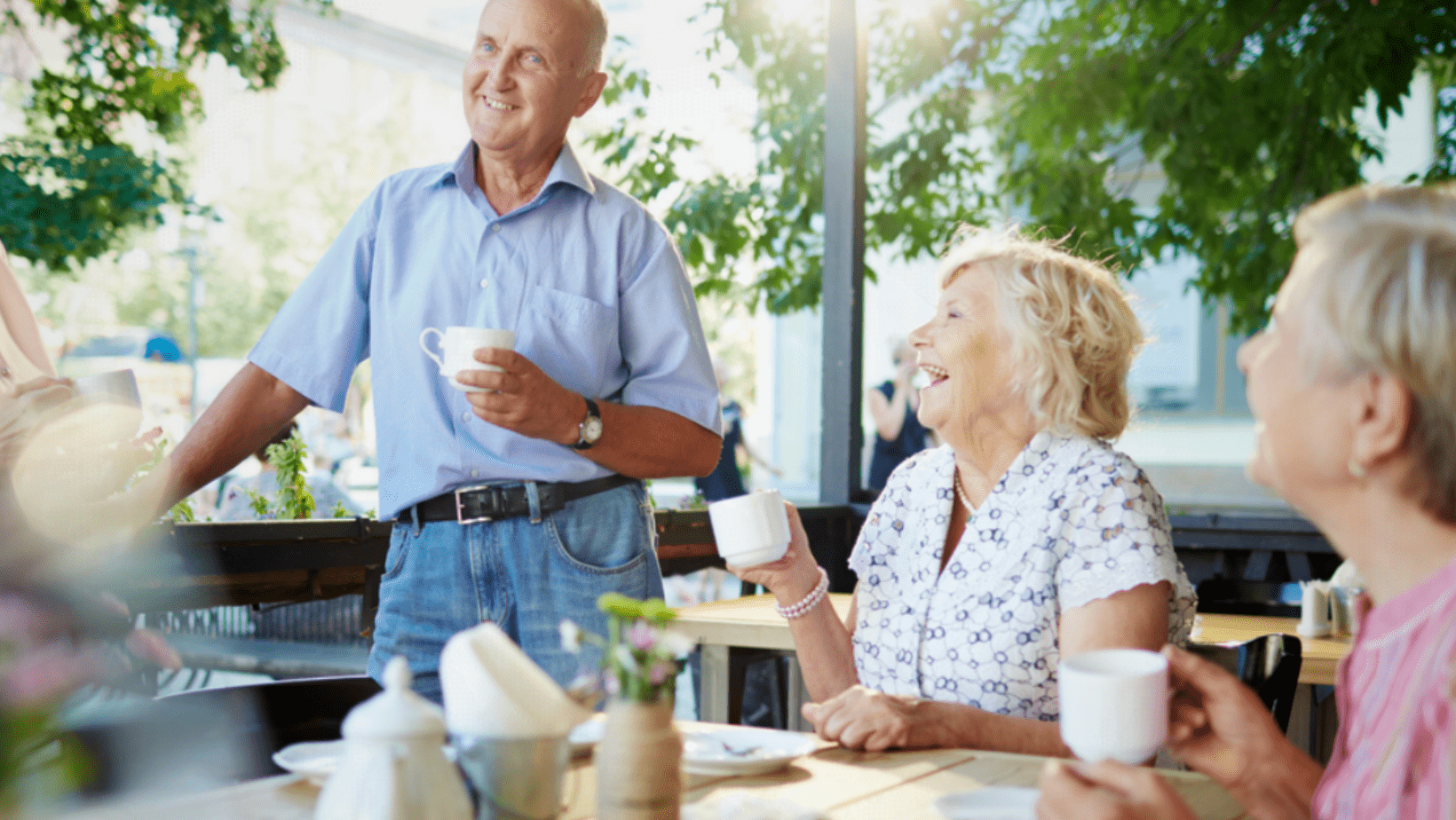 Older adults enjoying coffee and conversation together during a social gathering.