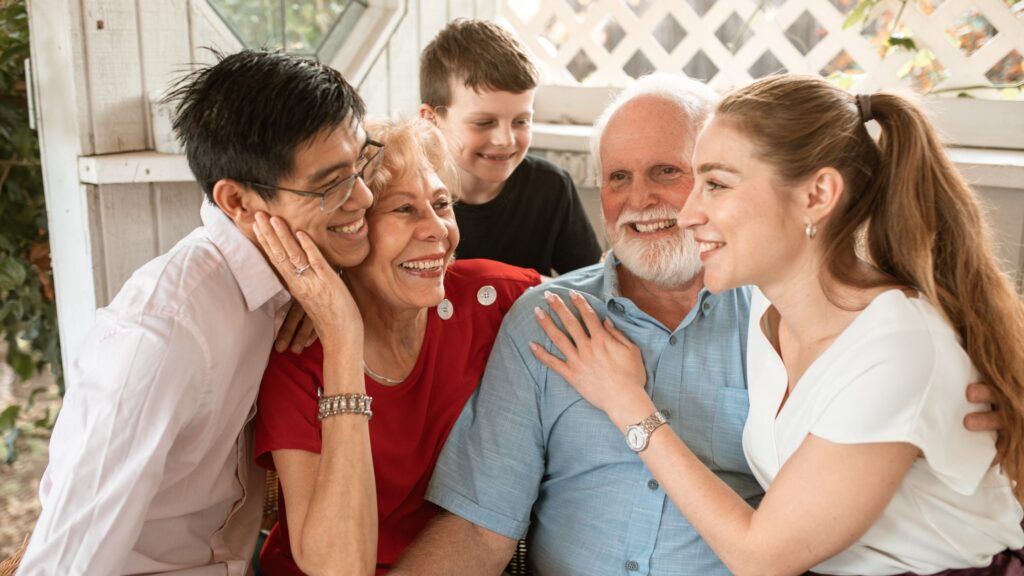 Older adults smiling with family during a social visit at home.