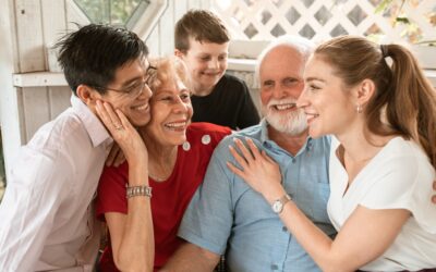 Older adults smiling with family during a social visit at home.
