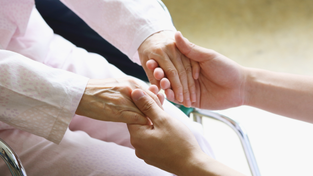 Caregiver holding a senior’s hands while providing compassionate home care in Eaton Rapids, MI.